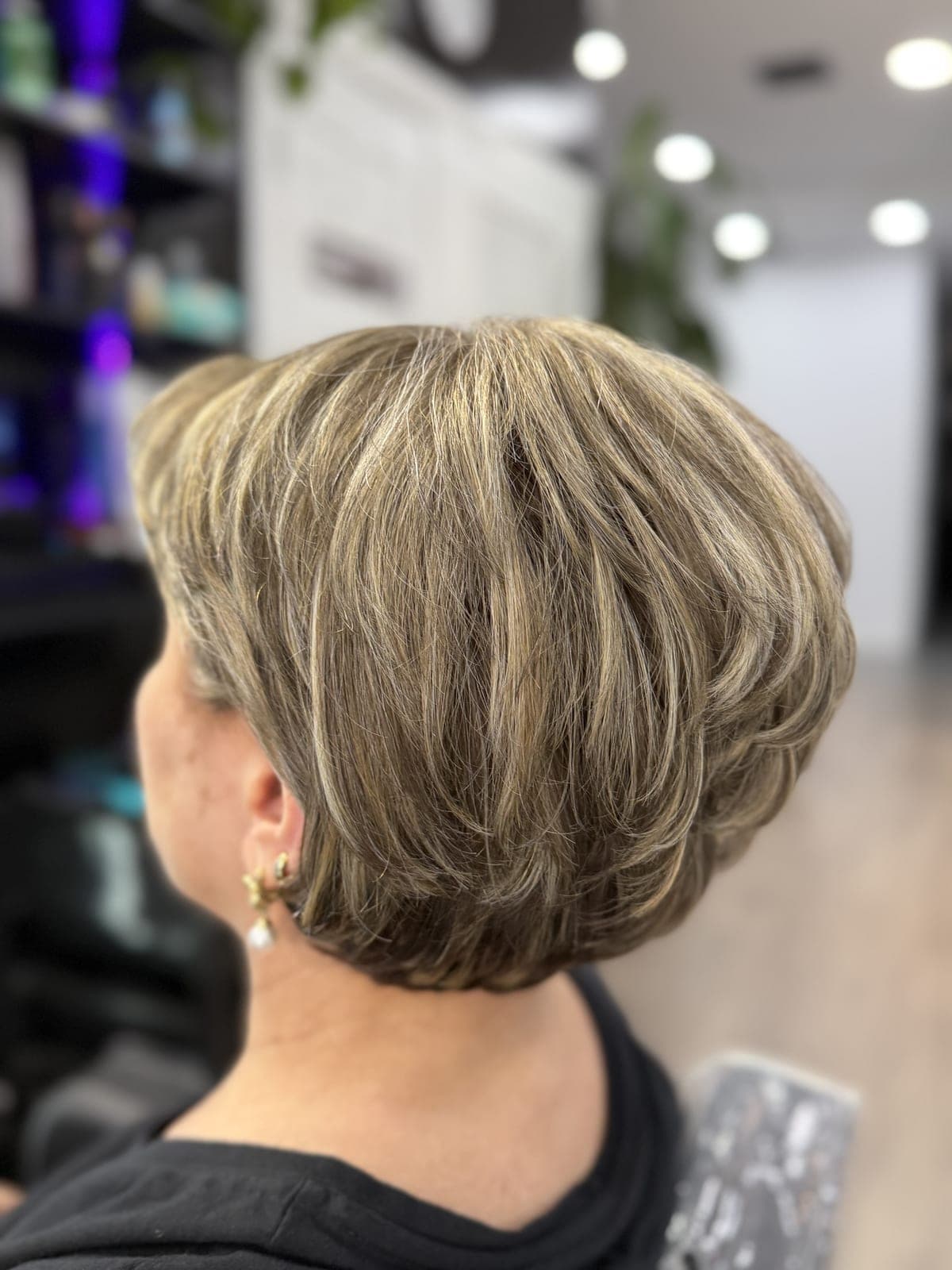 Short layered crop with fine blonde dimension blended over a darker base, seen from the back