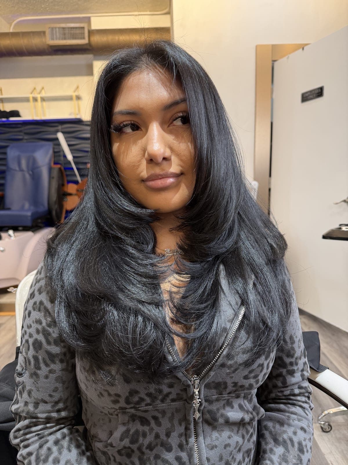 Client facing the camera with long dark hair cut in soft face-framing layers