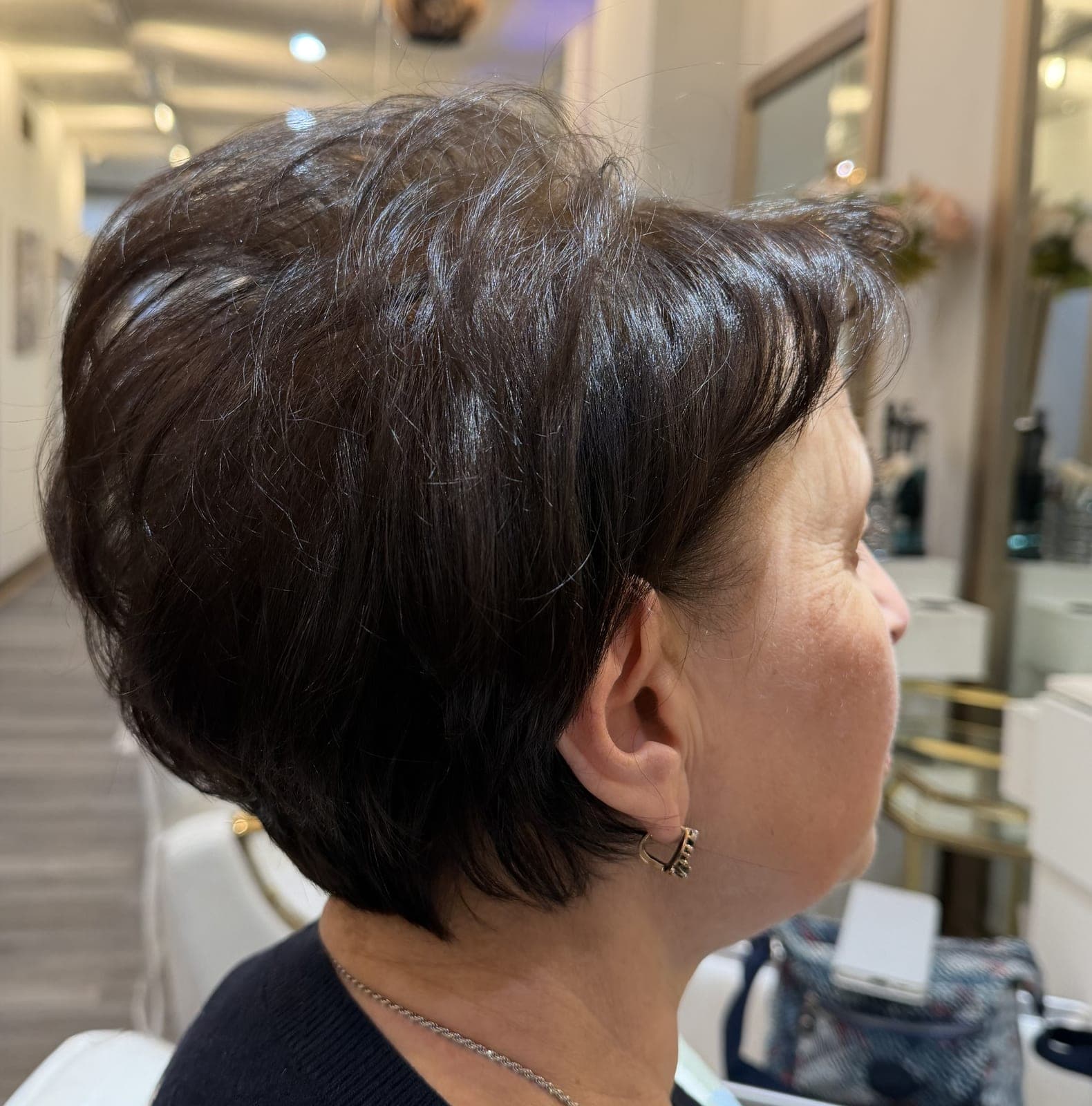 Short dark pixie cut with soft texture through the crown, seen from the side