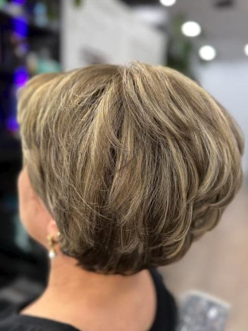 Short layered cut with gray fully blended into a warm blonde tone, seen from behind
