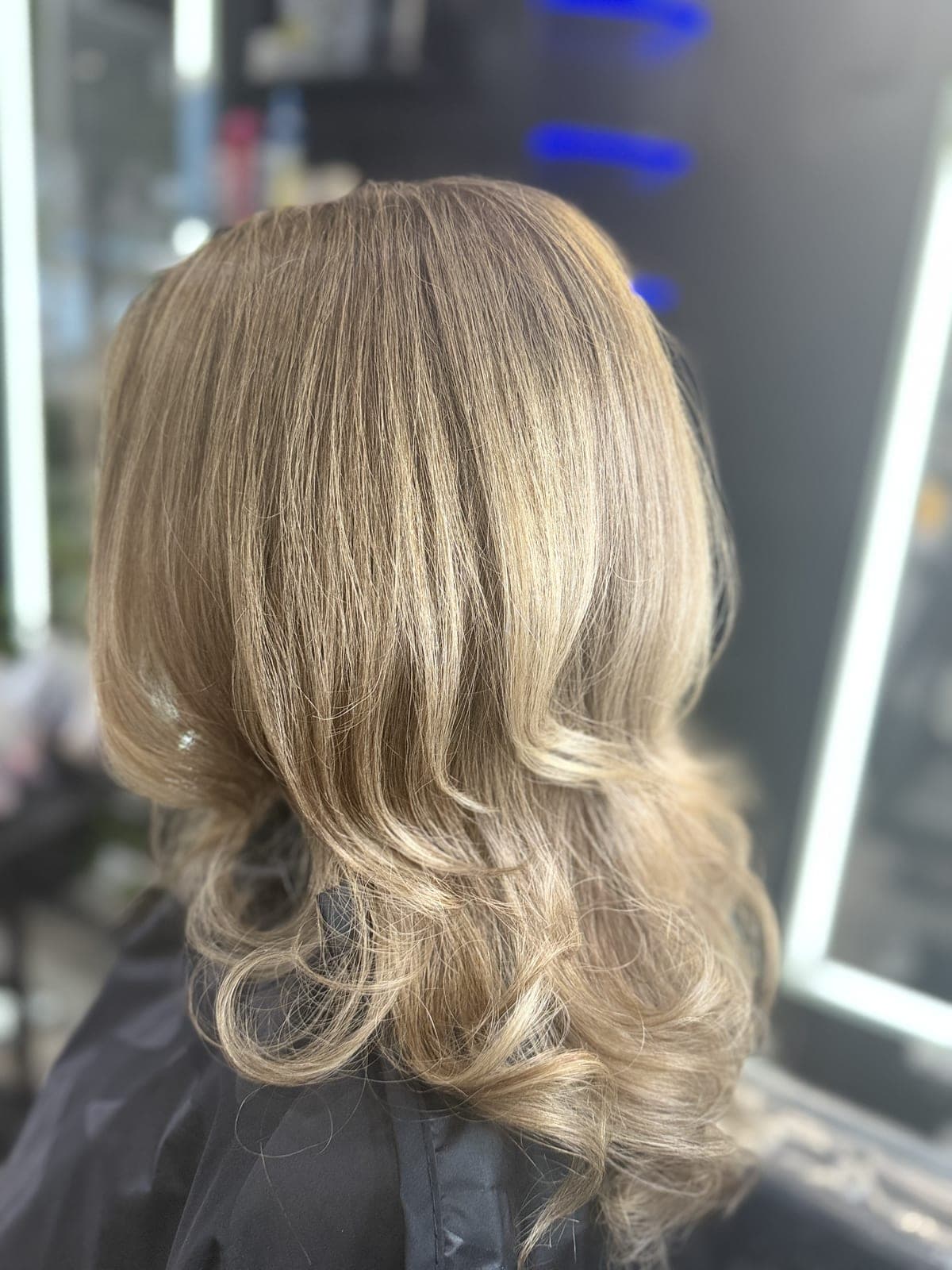 Champagne-blonde blowout with curled ends, seen from the back